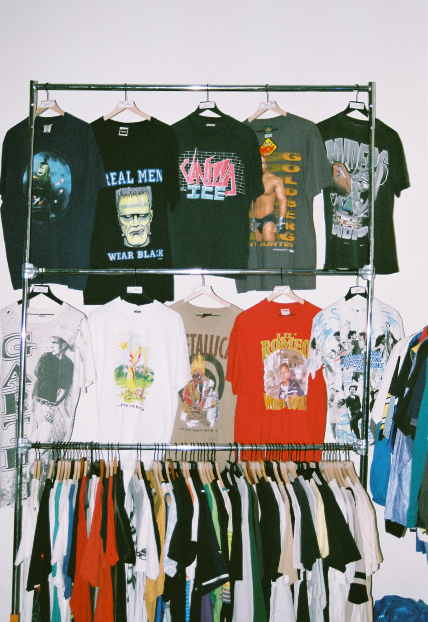 A rack of vintage band and graphic t-shirts — Metallica, wrestling, classic rock.